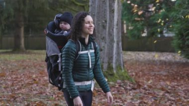 Annem Taşıyıcı Bebek 'le banliyö mahallesinde yürüyor. Sonbahar sezonu. Burnaby, Vancouver, BC Kanada. Yüksek kalite 4k görüntü