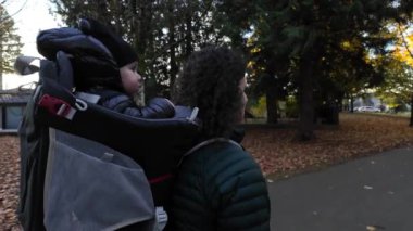 Annem Taşıyıcı Bebek 'le banliyö mahallesinde yürüyor. Sonbahar sezonu. Burnaby, Vancouver, BC Kanada. Yüksek kalite 4k görüntü