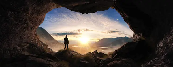 Adventurous Man Hiker standing in a cave. River and Mountains in background. Adventure Composite 3d Rendering. Aerial Image of landscape from BC, Canada. Sunset Cloudy Sky