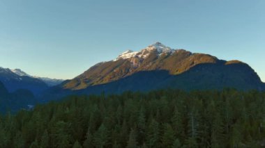 Kanada Dağ manzarası, tepesinde yeşil ağaçlar ve kar olan kayalar. Güneşli Mavi Gökyüzü. British Columbia, Kanada.