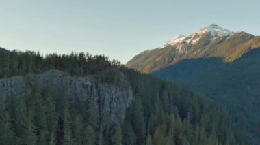 Kanada Dağ manzarası, tepesinde yeşil ağaçlar ve kar olan kayalar. Güneşli Mavi Gökyüzü. British Columbia, Kanada.