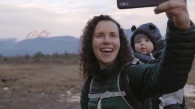 Anne ve bebek Kanada doğasında yürüyüş yapıyor. Selfie çekiyorum. Sonbahar sezonu, Günbatımı. Squamish, Britanya Kolombiya Kanada 'sı. Yavaş Hareket