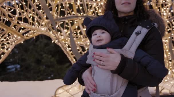 Mutter Mit Entzückendem Baby Tragetuch Beim Anblick Der Weihnachtsbeleuchtung Winterzeit — Stockvideo