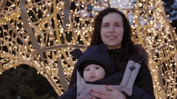 Moeder Met Schattige Baby Boy Carrier Kijkend Naar Kerstverlichting Winterseizoen — Stockvideo