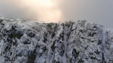 Rocky Cliffs bulutlu kış gününde karla kaplıydı. BC, Kanada. Havadan.