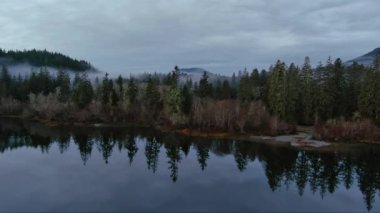 Çevresi dağlarla, ağaçlarla çevrili Manzaralı Vadi ve Göl. Sisli Sabah. Kanada Vahşi Doğası Hava Arkaplanı. Vancouver Adası, BC, Kanada.