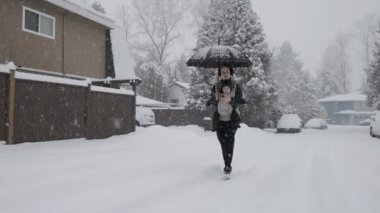 Anne, Karlı Gün 'de Sevimli Bebek ile Öndeki Taşıyıcı' da yürüyor. Kış mevsimi. Mahalle yürüyüşü. Burnaby, MÖ Vancouver Kanada.