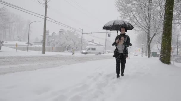 スノーウィーデーのフロントキャリアで愛らしい赤ちゃんと一緒に歩く母親 冬のシーズン 近所ウォーク バーナビー バンクーバー カナダ — ストック動画