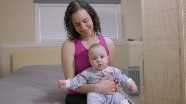 かわいい赤ん坊を抱えている母親は ベッドの上で家に座っています 笑顔で ハッピー 愛らしい — ストック動画