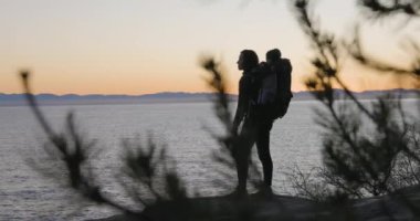 Anne ve Baby Boy sırt çantasıyla Rocky Okyanusu kıyısında yürüyüş yapıyor. Fener Parkı, Batı Vancouver, BC, Kanada.