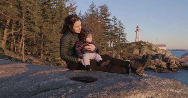 Matka Chlapeček Sedí Skále Malebného Mořského Pobřeží Maják Pozadí Západ — Stock video
