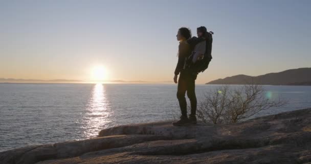 ロッキー海岸でハイキングバックパックキャリアの母とベビーボーイ ライトハウスパーク ウェストバンクーバー カナダ — ストック動画