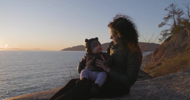 美しい海岸でロックに座っている母と赤ちゃんのボーイ サンセット ライトハウスパーク ウェストバンクーバー カナダ — ストック動画
