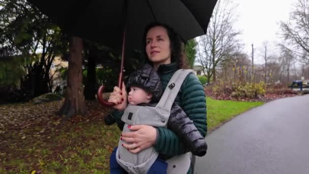 フロントで母親とかわいい赤ちゃんの少年がキャリアに直面し 近所の道を歩いています 雨の日 バーナビー バンクーバー カナダ — ストック動画