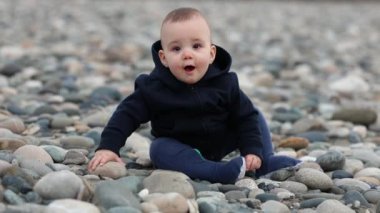 Tatlı bebek nehir kıyısındaki Rocky Shore 'da oturuyor. Bahar sezonunda gün batımı. Chilliwack, İngiliz Kolombiyası, Kanada.