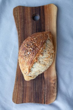 Tahta üzerinde tahıllar olan taze pişmiş ekmek. Ayçekirdeği, keten tohumu ve ekmek. Tereyağlı Fransız tahıl ekmeği