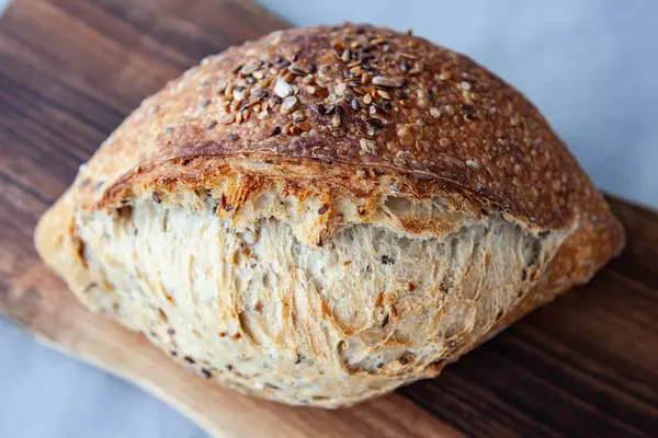 Tahta üzerinde tahıllar olan taze pişmiş ekmek. Ayçekirdeği, keten tohumu ve ekmek. Tereyağlı Fransız tahıl ekmeği
