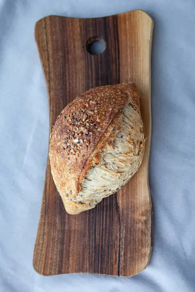 Tahta üzerinde tahıllar olan taze pişmiş ekmek. Ayçekirdeği, keten tohumu ve ekmek. Tereyağlı Fransız tahıl ekmeği