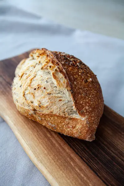 Tahta üzerinde tahıllar olan taze pişmiş ekmek. Ayçekirdeği, keten tohumu ve ekmek. Tereyağlı Fransız tahıl ekmeği