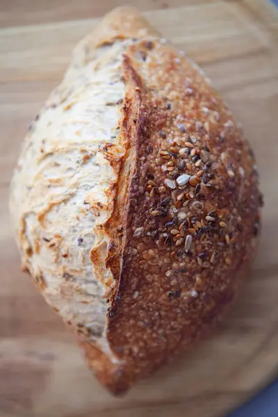 Tahta üzerinde tahıllar olan taze pişmiş ekmek. Ayçekirdeği, keten tohumu ve ekmek. Tereyağlı Fransız tahıl ekmeği