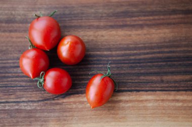 Tahtadaki kiraz domatesleri ve yeşil yapraklar 