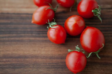 Tahtadaki kiraz domatesleri ve yeşil yapraklar 