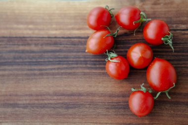 Tahtadaki kiraz domatesleri ve yeşil yapraklar 