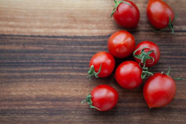 Tahtadaki kiraz domatesleri ve yeşil yapraklar 