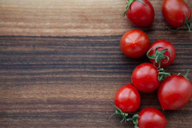 Tahtadaki kiraz domatesleri ve yeşil yapraklar 