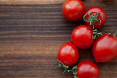 Tahtadaki kiraz domatesleri ve yeşil yapraklar 