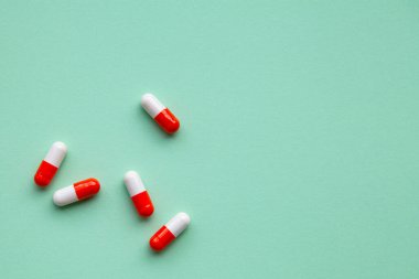 Yeşil arka planda beyaz ve turuncu haplar, birbirinden uzak. İlaç, sağlık, eczane, sağlık. Boşluğu kopyala.