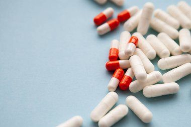 Beyaz ve beyaz-turuncu haplar mavi arka plana saçılmış. yakın plan