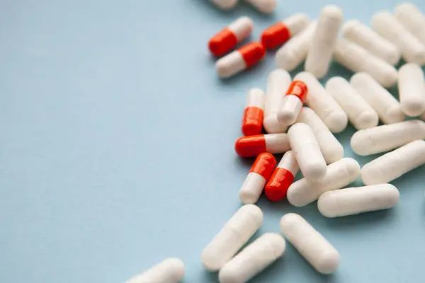 Beyaz ve beyaz-turuncu haplar mavi arka plana saçılmış. yakın plan