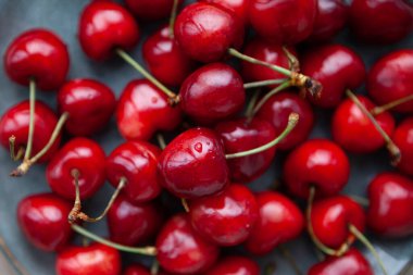 Tahta bir masanın arka planındaki sepetin içindeki kirazlar, üst manzara..