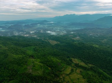 Yoğun bir tropik dağ ormanının üzerinde parlayan çarpıcı bir güneş doğumu görüntüsü..