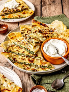 Gözleme adı verilen ıspanak ve peynirle doldurulmuş geleneksel Türk ekmeği, bir toprak tabağında ekşi kremayla servis ediliyor.