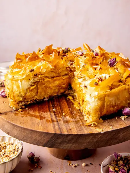 Şam fıstıklı, ballı ve gül yapraklı baklava cheesecake pembe masada servis edilir.