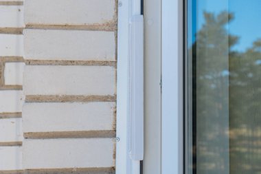 Pencere çerçevesinde havalandırma giriş vanası var. Modern bir tuğla binada plastik pencere çerçevesine monte edilmiş, duvara monte edilmiş havalandırma vanası..