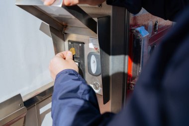 Adam oto yıkama terminaline bozuk para yerleştiriyor, çamaşır makinesini çalıştırmaya ve arabasını temizlemeye hazırlanıyor..