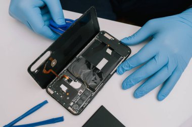 Beyaz arka planda parçalanmış bir akıllı telefon. Kayıp bir batarya karşılaştırması ve hasarlı, şişmiş bir eski. Elektronik tamir ve bakım konsepti