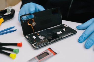 Beyaz arka planda parçalanmış bir akıllı telefon. Kayıp bir batarya karşılaştırması ve hasarlı, şişmiş bir eski. Elektronik tamir ve bakım konsepti