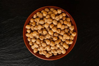 Siyah bir zemin üzerinde altın rengi, izole edilmiş, üst görünümü, çiğ baklagiller, sağlıklı organik yiyecekler, yüksek proteinli vejetaryen malzemeler, besleyici kuru bezelyeler, tarım hasadı.,