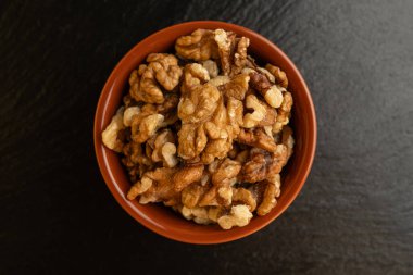 Siyah arka planda bir kasede ceviz kabı, izole, üst görünüm, çıtır çıtır ve besleyici atıştırmalık, sağlıklı organik gıda, yüksek proteinli vejetaryen malzeme