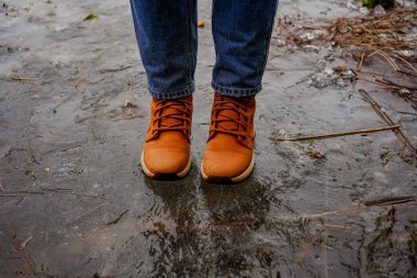 İnce buz üzerinde dikkatlice yürüyen kişi donmuş bir gölde, kış manzarasında, riskli bir macerada, doğada ihtiyatlı.