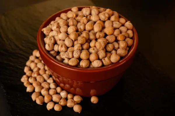 Siyah arka planda bir kasedeki nohut, izole edilmiş, çiğ baklagiller, sağlıklı organik yiyecekler, yüksek proteinli vejetaryen malzemeler, besleyici kuru bezelyeler, tarım hasadı.,