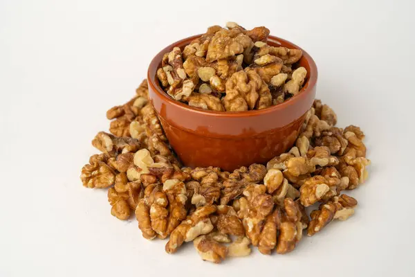 Beyaz arka planda kabuklu ceviz kabuğu, dağınık çekirdekler, izole, gevrek ve besleyici atıştırmalıklar, sağlıklı organik yiyecekler, yüksek proteinli vejetaryen malzemeler, soyulmuş ceviz parçaları.