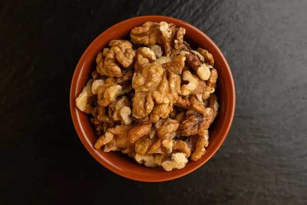 Siyah arka planda bir kasede ceviz kabı, izole, üst görünüm, çıtır çıtır ve besleyici atıştırmalık, sağlıklı organik gıda, yüksek proteinli vejetaryen malzeme