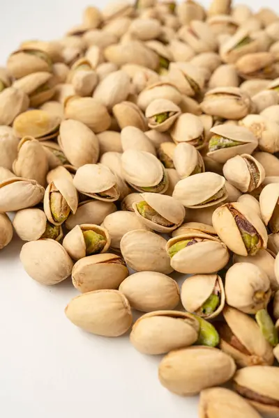 Beyaz arka planda bir sürü tuzlu şam fıstığı, izole edilmiş, üst düzey, kızarmış fındık, lezzetli ve besleyici aperatif, sağlıklı organik yiyecek, yüksek proteinli vejetaryen malzeme, kabuklu fıstık.