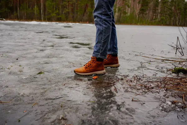 İnce buz üzerinde dikkatlice yürüyen kişi donmuş bir gölde, kış manzarasında, riskli bir macerada, doğada ihtiyatlı.