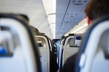 Yolcuların sıra sıra oturduğu bir uçak kabininin içinde. Hava yolculuğu ve ulaşım kavramı.